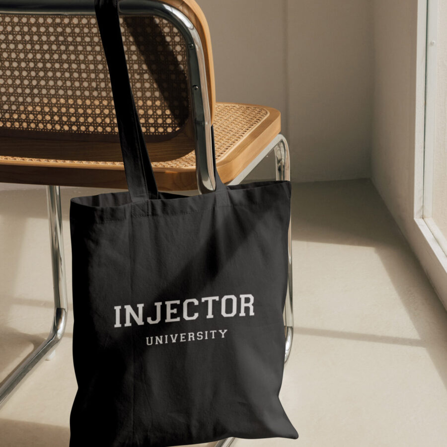 Injector University black cotton tote bag hanging on chair